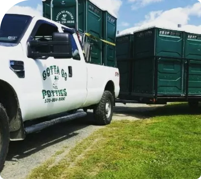 a white truck delivering green porta potty units