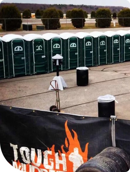 a line of multiple green porta potties at an outdoor event